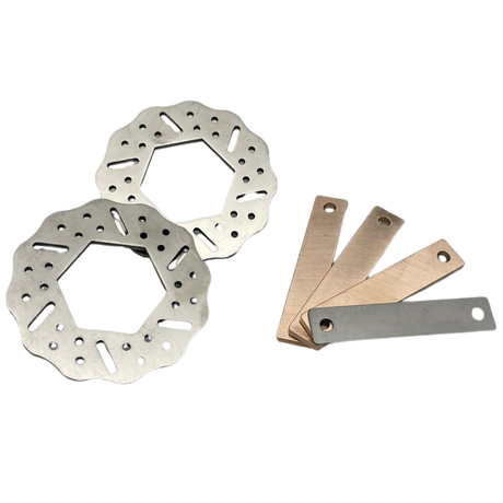 Two metal brake rotors and three metal feeler blades on a white background