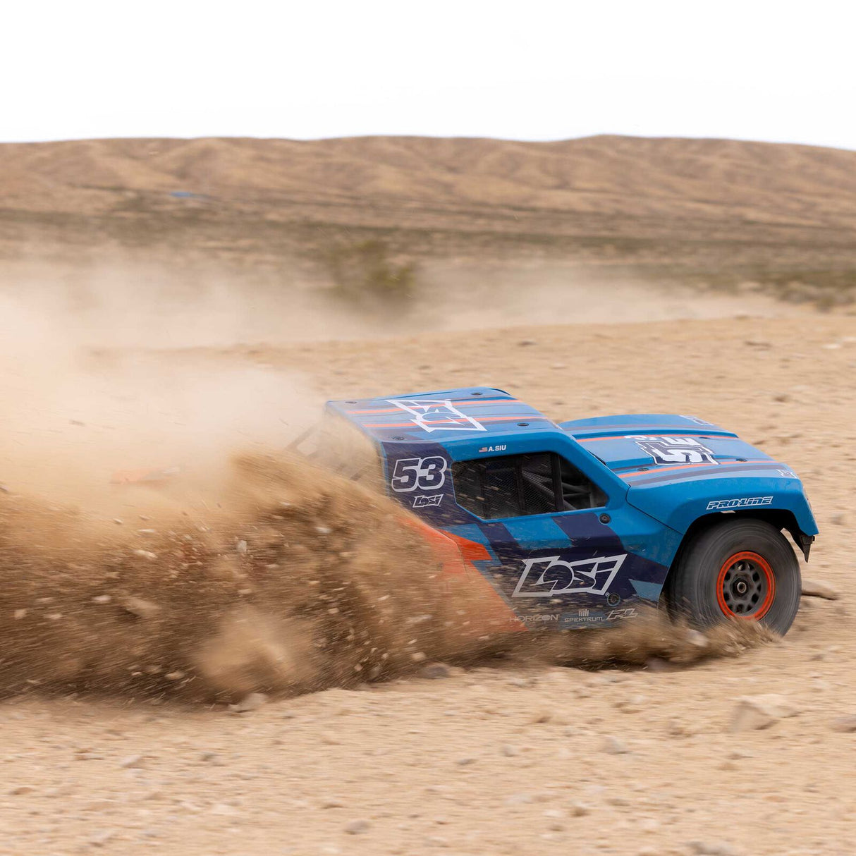 Blue off-road racing truck with number 53 driving on a dirt track