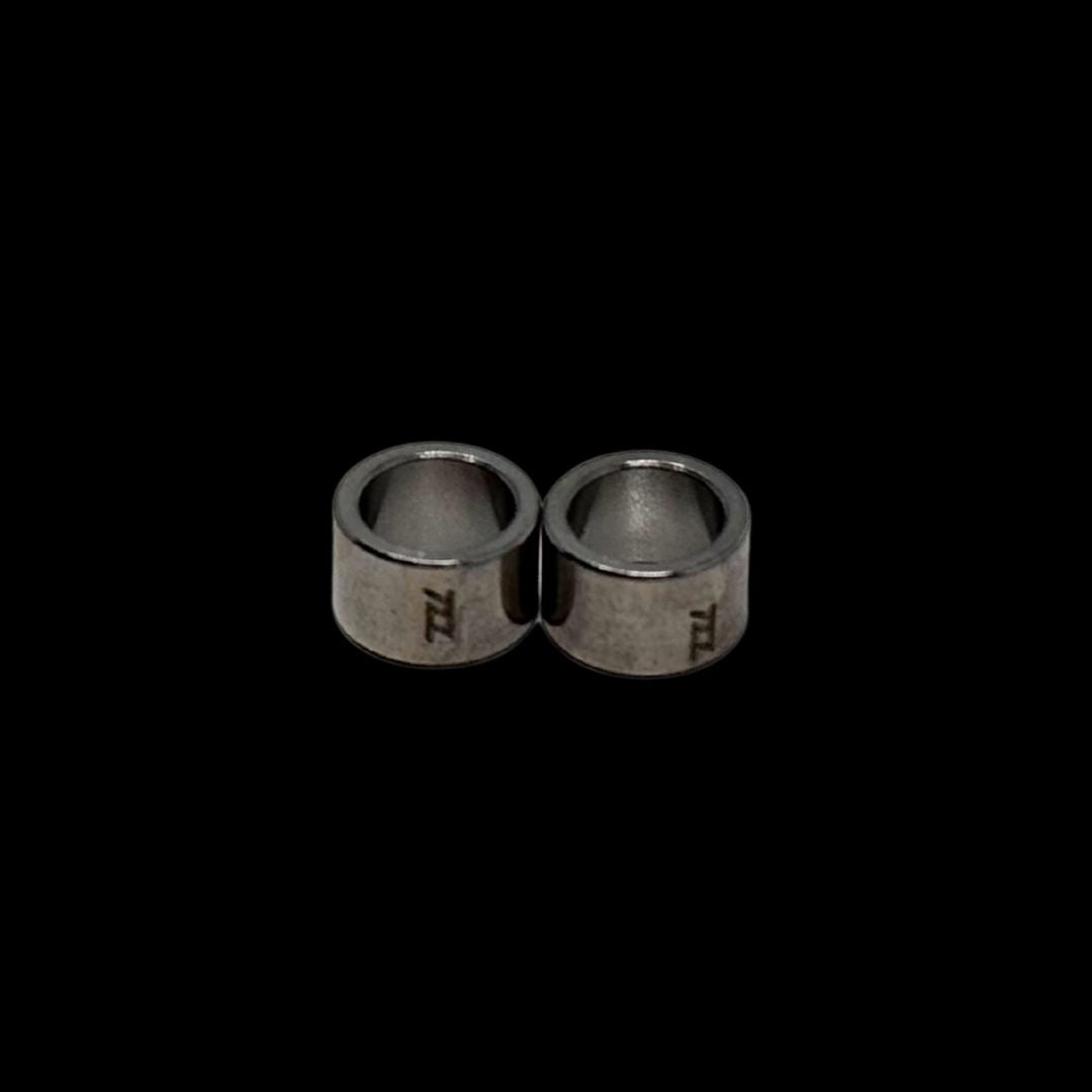 Pair of silver bushings with engraved tzz logo on a black background