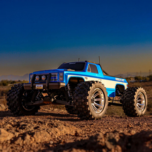 Blue monster truck on a dirt road with a clear sky