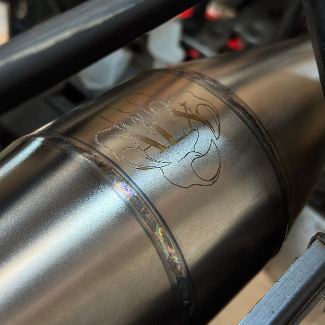 Close-up of the engraved ALX logo on a titanium exhaust pipe