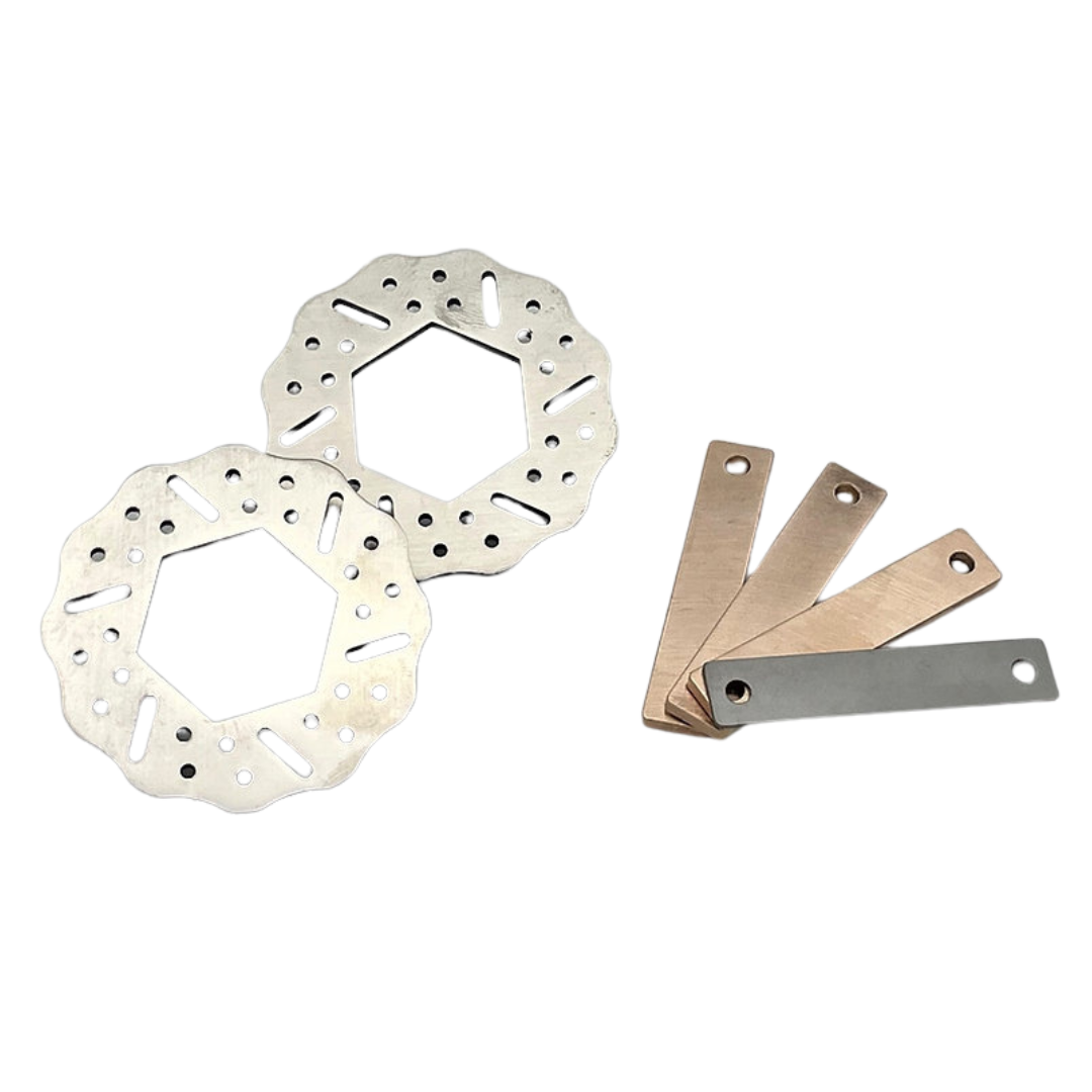 Two metallic brake rotors and four metal shims on a white background