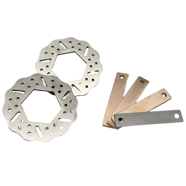 Two metal brake rotors and three metal feeler blades on a white background