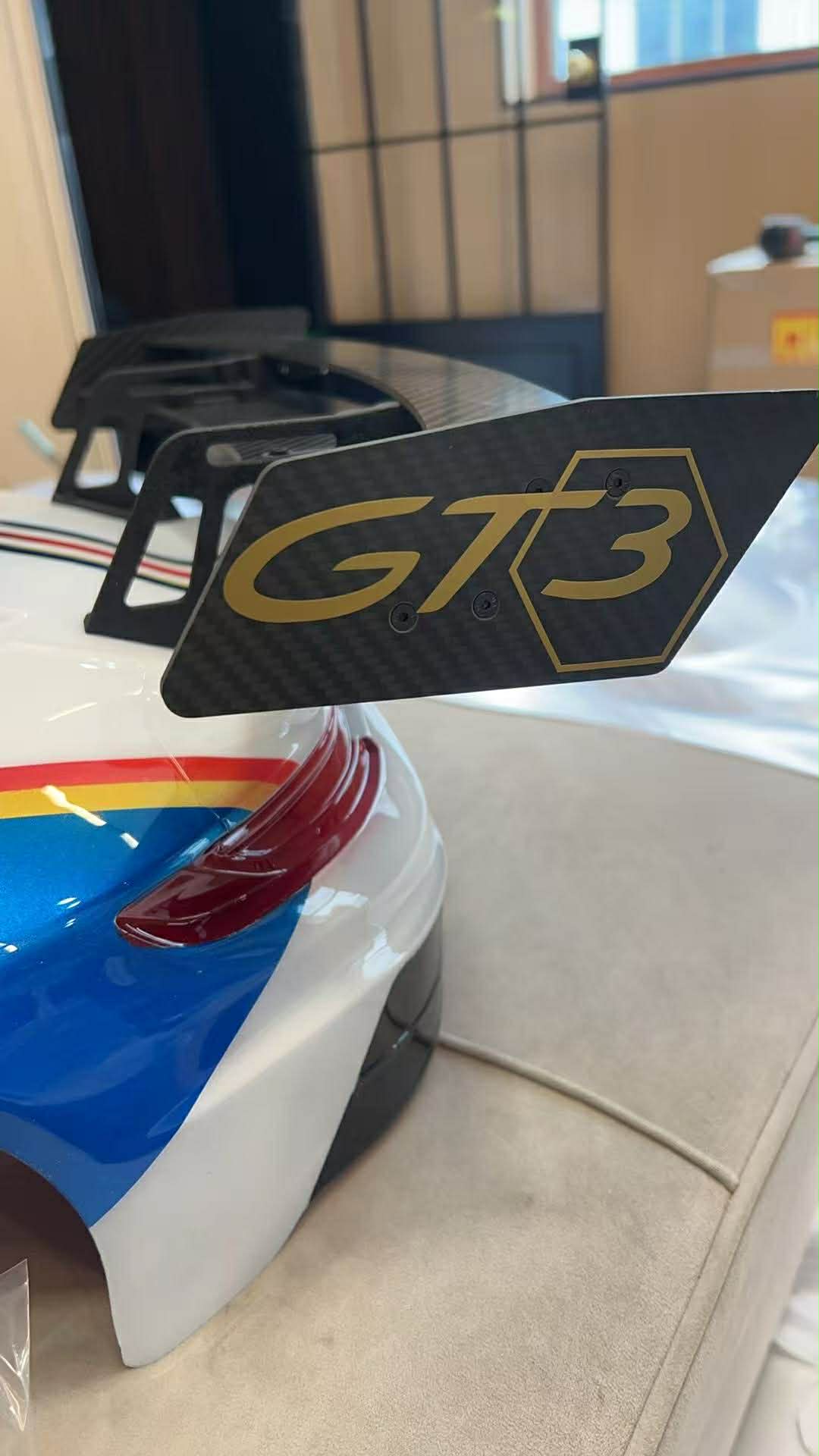 Car spoiler with 'GT3' logo on a vehicle in a showroom.