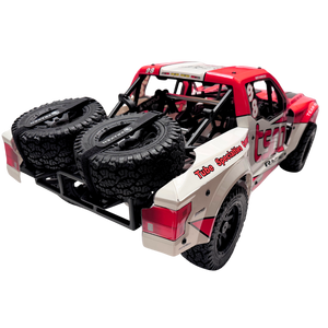 Red and beige off-road model truck with large black tires on a white background