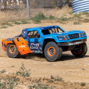 Blue and orange off-road model truck on a dirt track