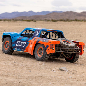 Off-road racing truck in a desert setting with mountains in the background