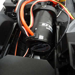 Close-up of a black cylindrical component with visible branding on a mechanical background.