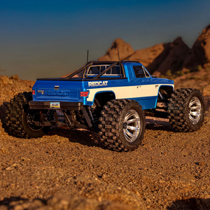 Blue and white RC truck on a desert landscape with rocky formations.