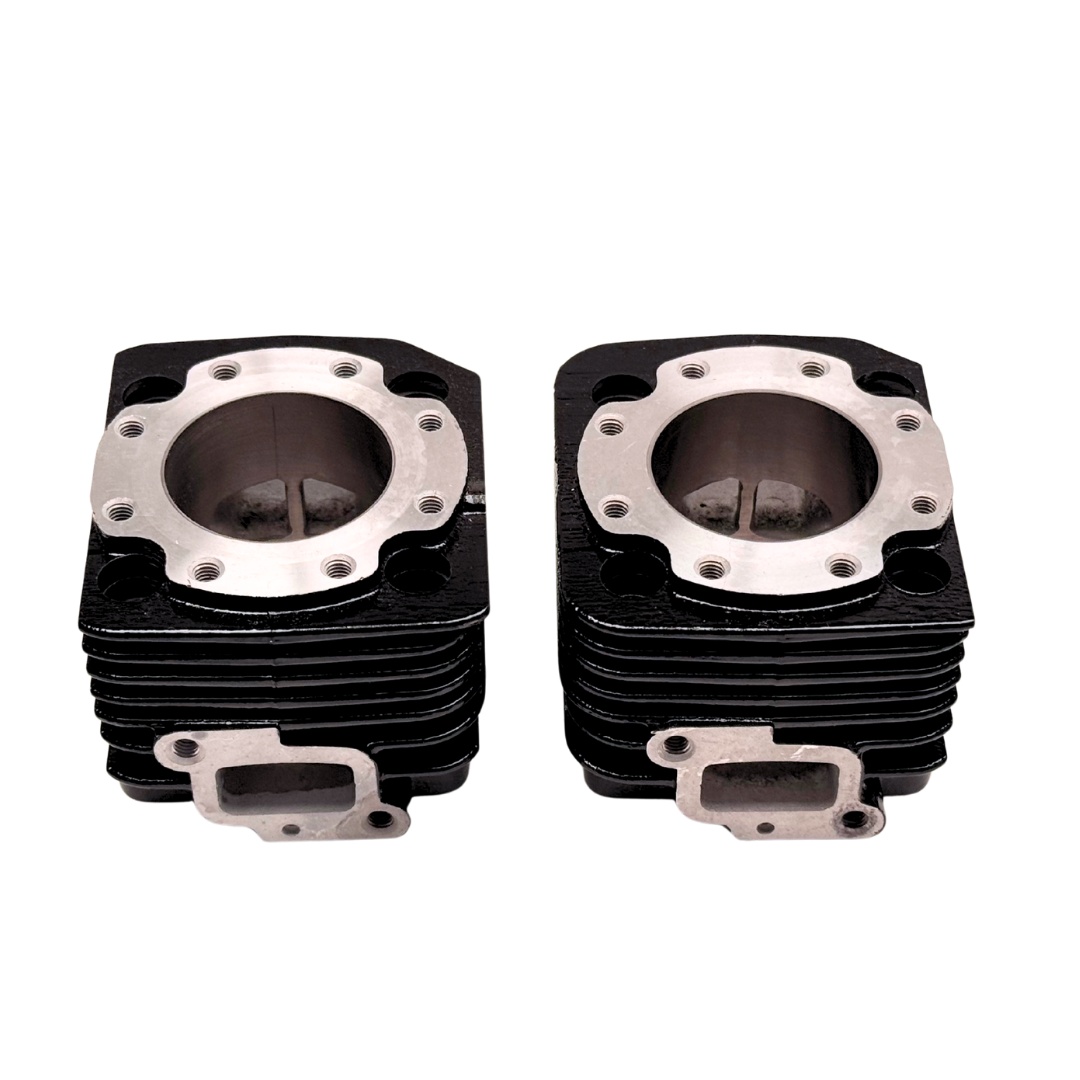 Two black and silver engine cylinder heads on a white background