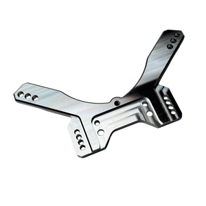 Taylor RC OUTLAW drop rear shock tower in raw silver, angled view showing the shock mounting holes, arm slots, and central chassis clearance cutout