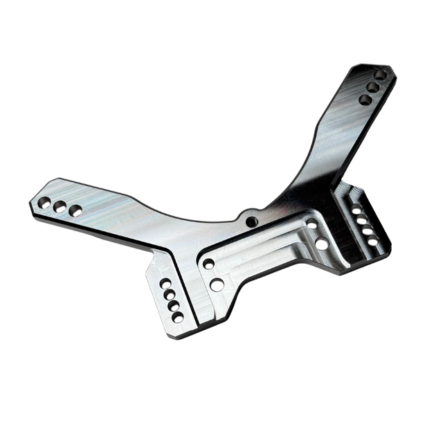 Taylor RC OUTLAW drop rear shock tower in raw silver, angled view showing the shock mounting holes, arm slots, and central chassis clearance cutout