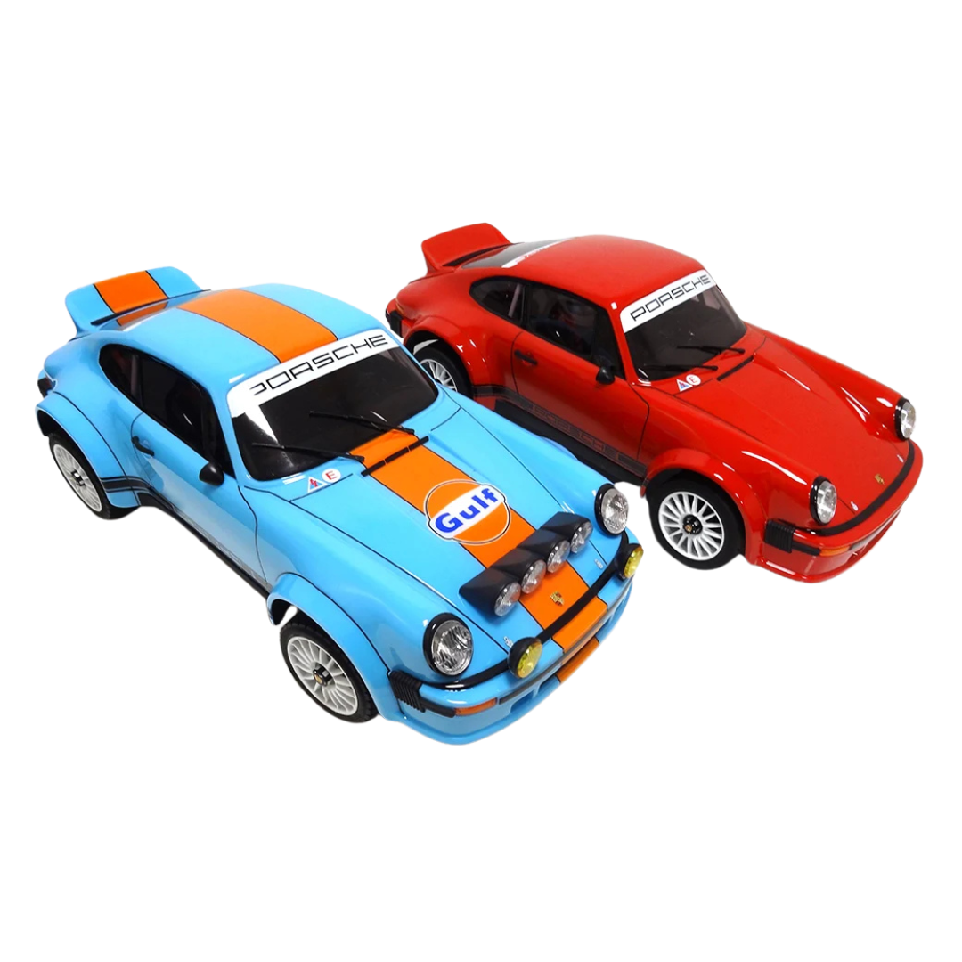 Two model cars, one blue and orange with Gulf livery, and one red with Porsche branding, on a white background.